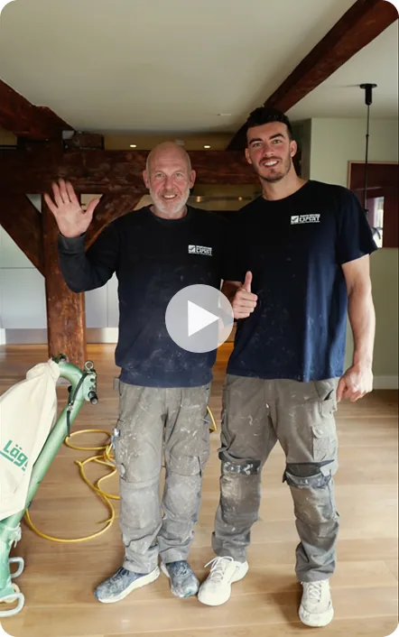 Vader en zoon aan het werk bij het schuren van een houten vloer